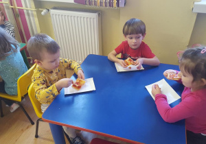 Dzieci zjadają pizzę ze smakiem.